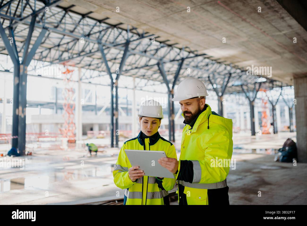 Engineers discussing construction plans using a tablet on site. Stock Photo