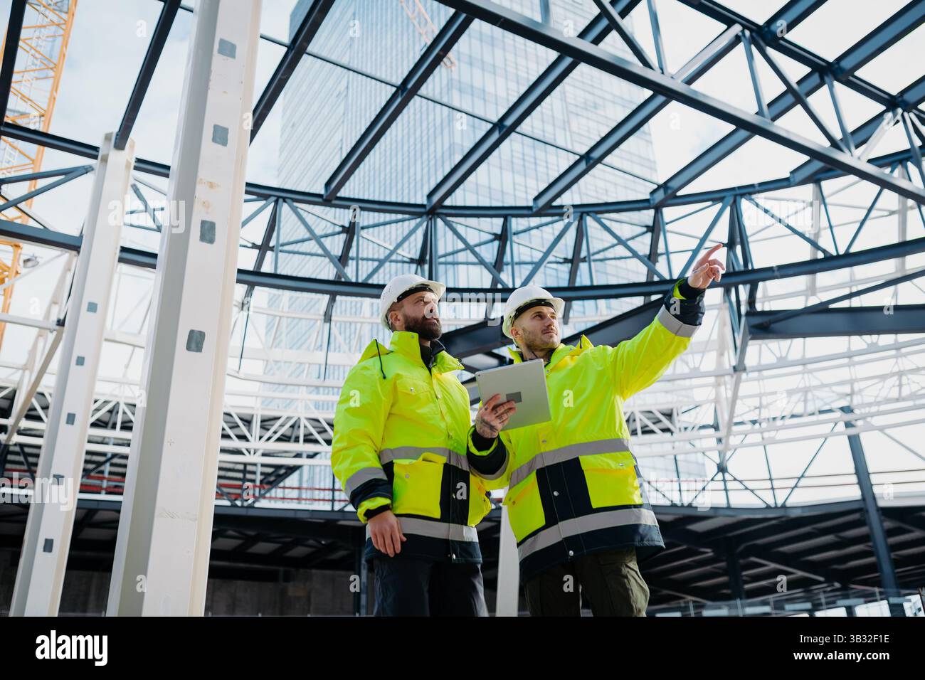 Construction managers using digital tablet on site, reviewing project plans. Stock Photo
