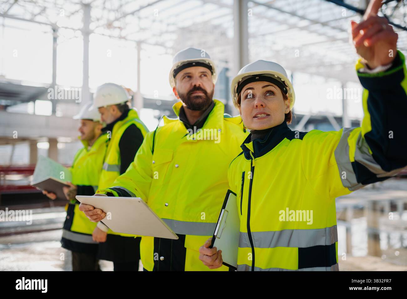 Team of engineers and construction workers inspecting building progress. Stock Photo