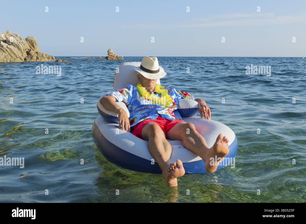 Senior man with spy glasses floating on chair in the sea Stock Photo