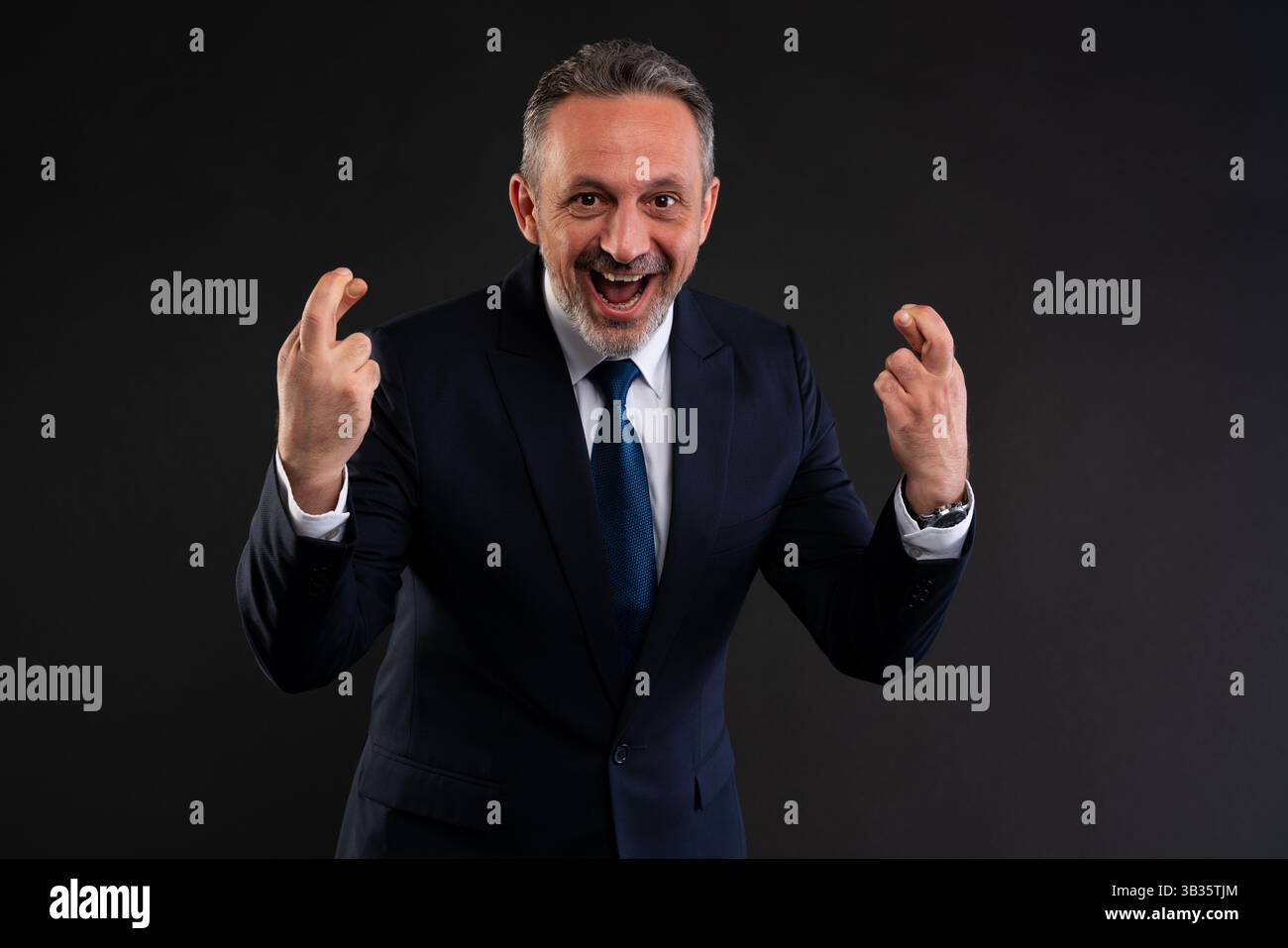 Joyful businessman in suit cheering with both hands raised and fingers ...