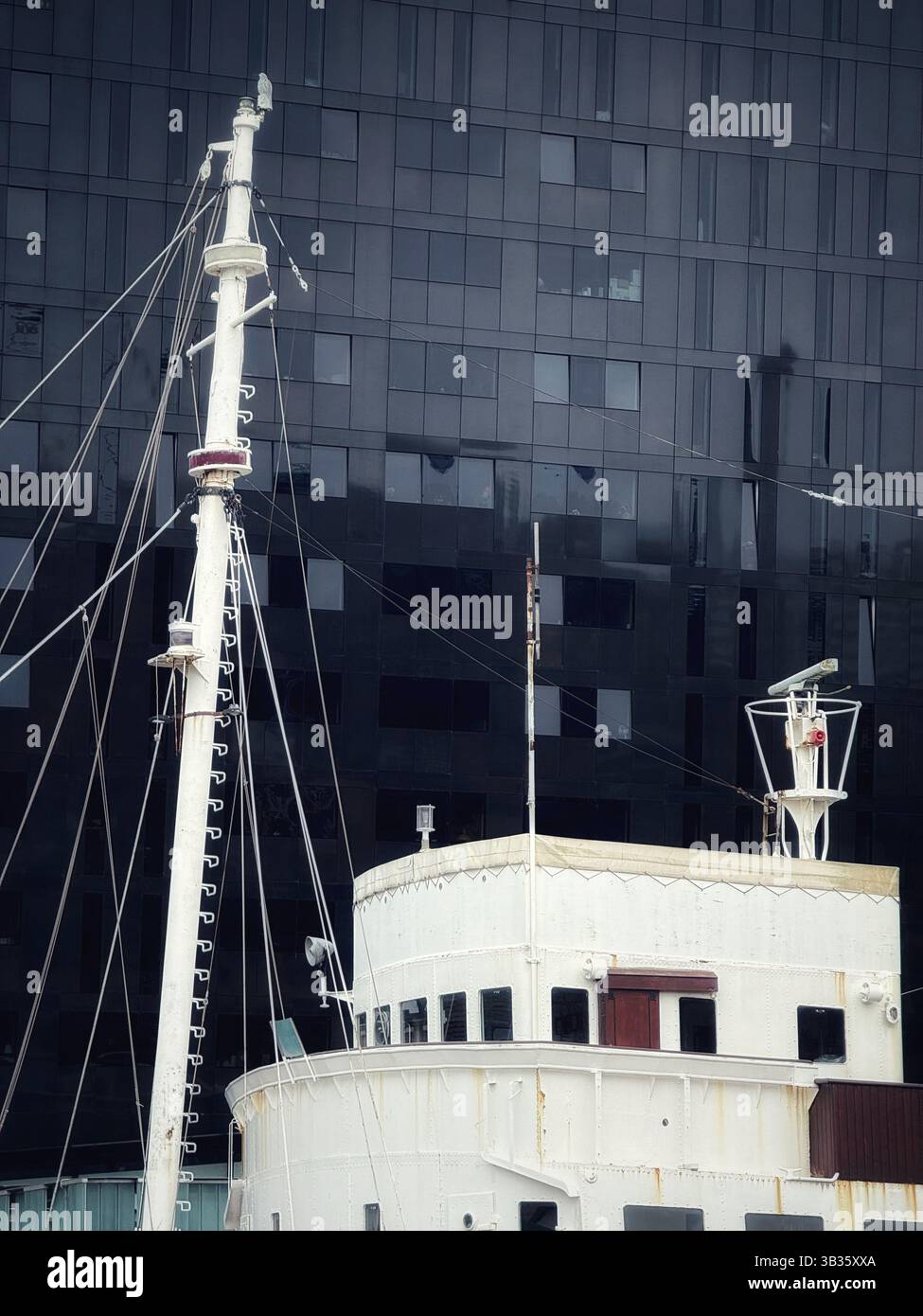 White painted superstructure of old boat contrasted against dark windows of modern office block - Smartphone Captured Stock Image