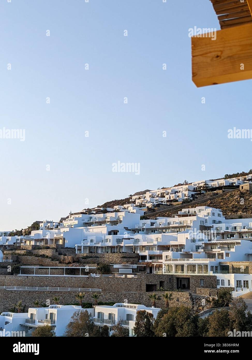 A view of painted white hotels and apartments on the hillside overlooking the Aegean Sea on the south coast of the Greek island, Mykonos - Smartphone Captured Stock Image