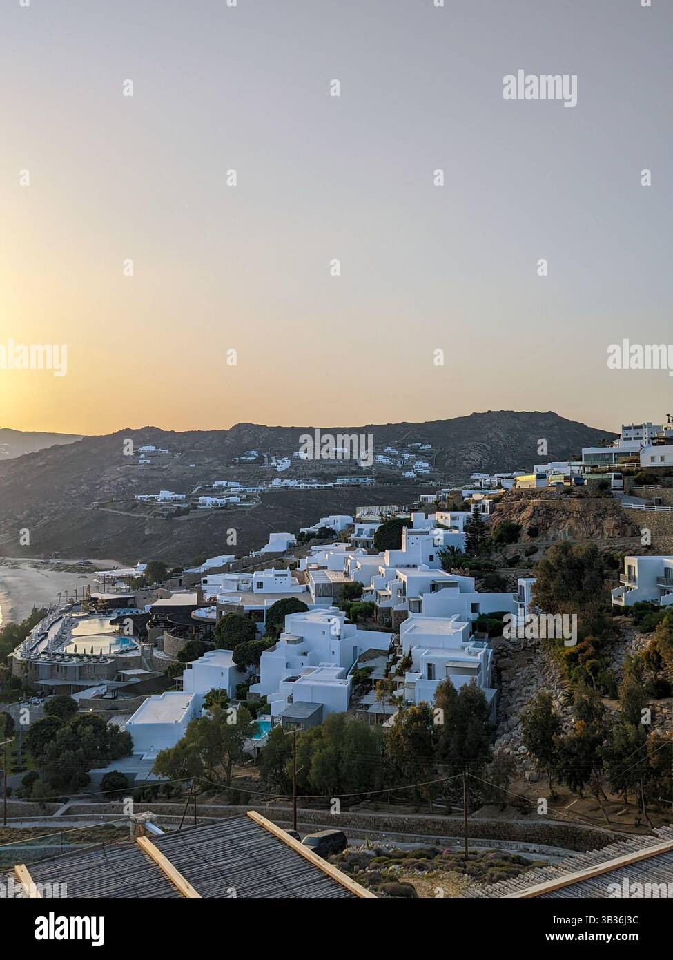 A view of painted white hotels and apartments on the hillside overlooking the Aegean Sea on the south coast of the Greek island, Mykonos - Smartphone Captured Stock Image