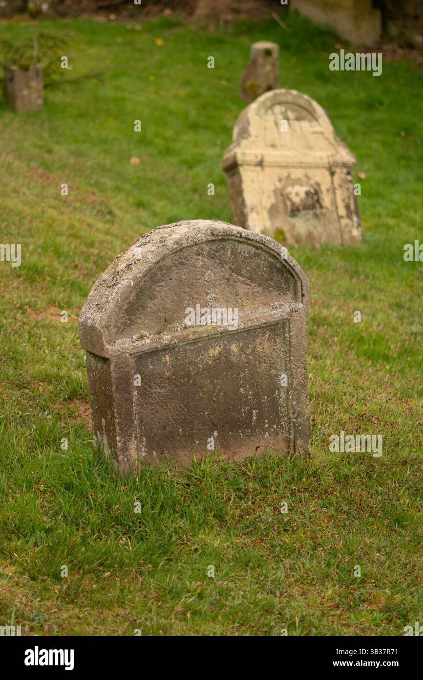 Old stone gravestone partially covered by moss, in a quiet cemetery ...