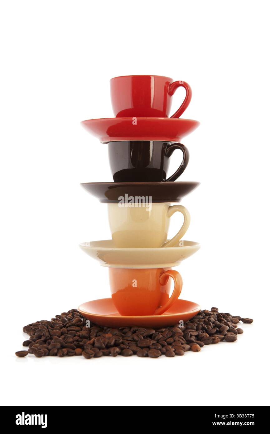 Stacked cups and saucers with coffee beans isolated over white background Stock Photo