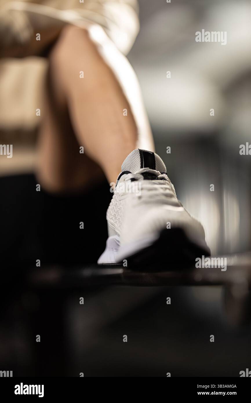 Athletic footwear is prominently displayed while person prepares for intense workout indoor gym. environment is energized equipment in background Stock Photo