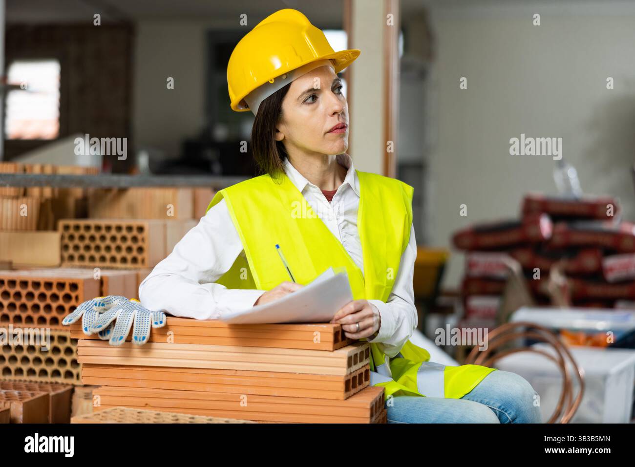 Female supervisor taking notes while inspecting construction site indoors Stock Photo