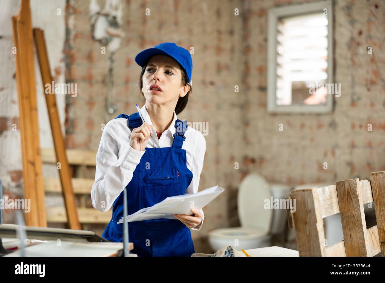 Female designer making checklist while planning building overhaul Stock Photo