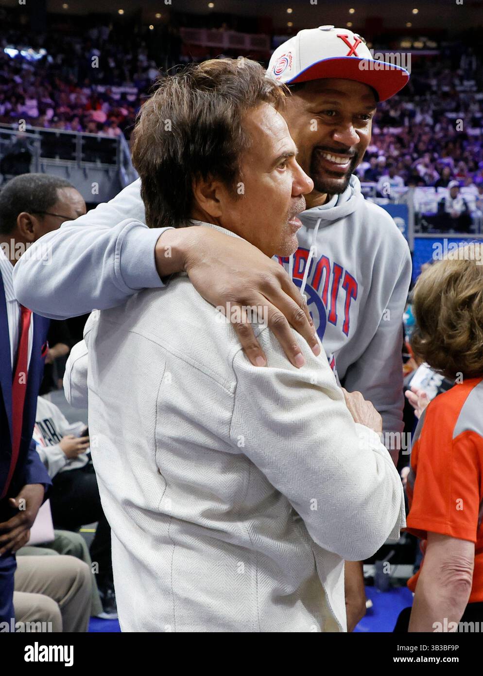 Former NBA player Jalen Rose, right, embraces Detroit Pistons owner Tom Gores before Game 4 of