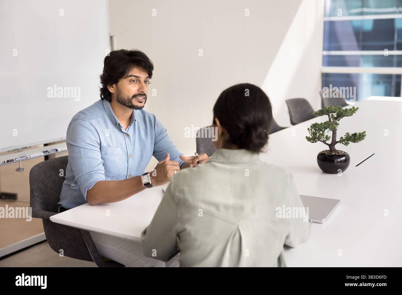 Teammates lead conversation about joint task seated at table Stock Photo