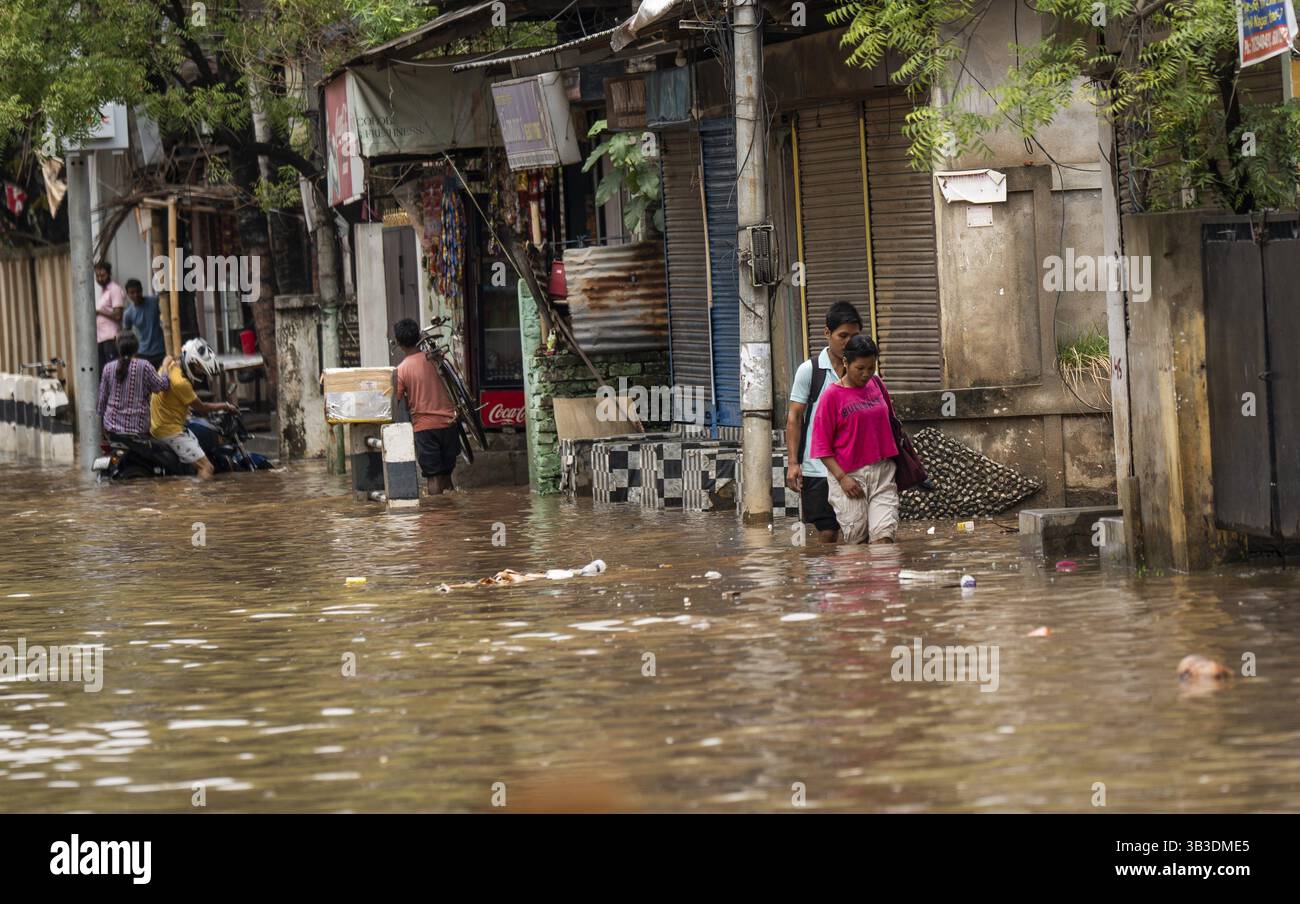 Commuters wade through a flooded street after heavy rains in Guwahati ...