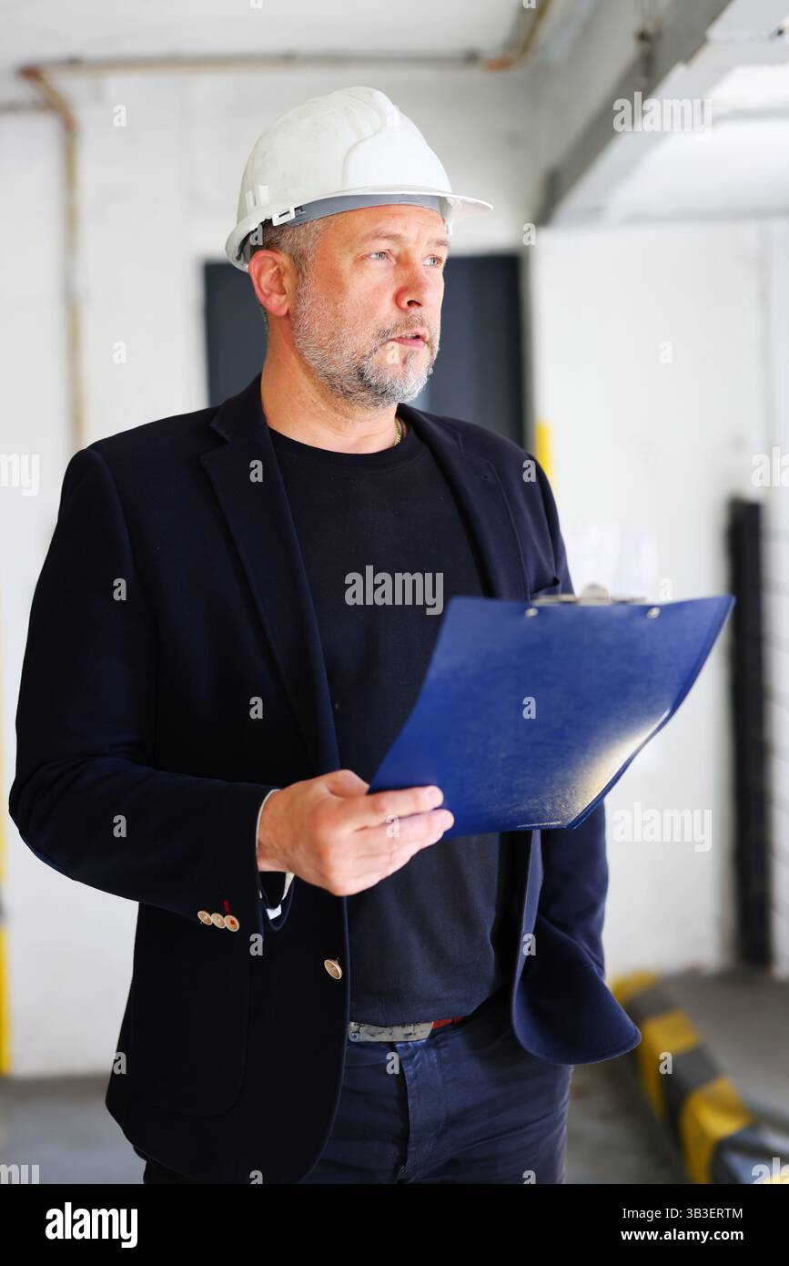 Professional engineer or foreman evaluating progress at work site, indoor setting. Stock Photo