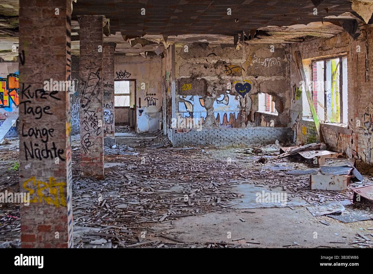 Abandoned brick interior filled with graffiti, fallen debris, and decaying structural walls. Stock Photo