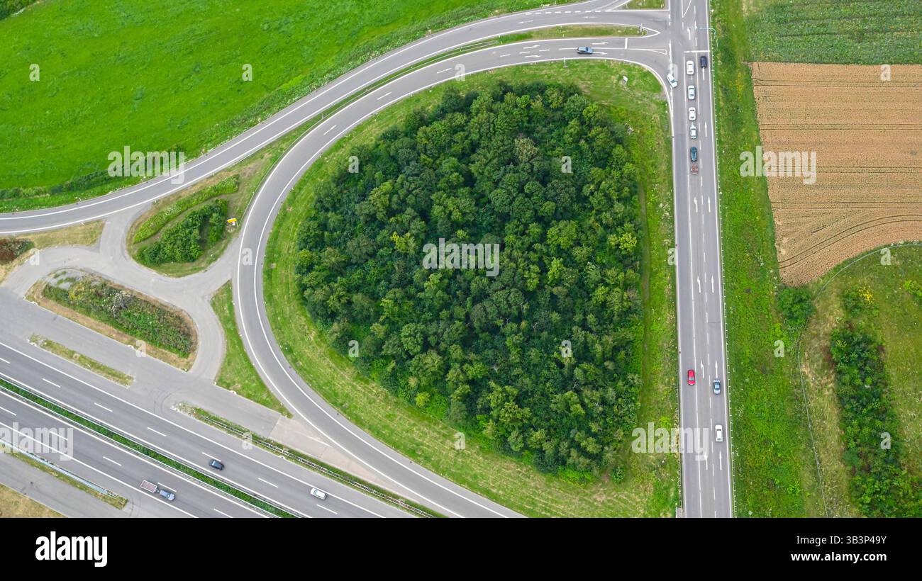 Country road, highway and traffic circle with exit and entry from above with drone view or from an airplane with vehicles; trucks and cars on the road. Stock Photo
