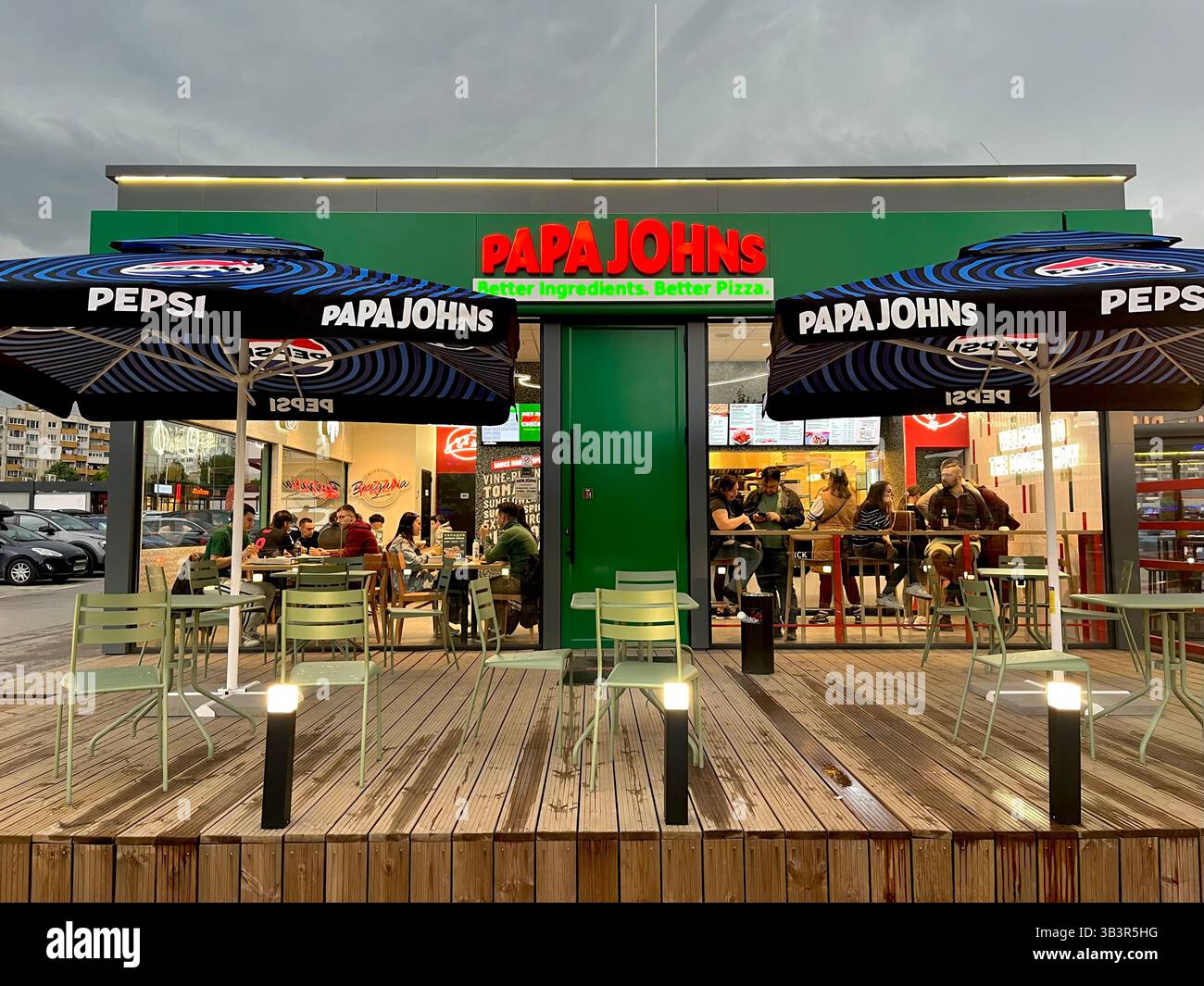 People dining indoors at a Papa Johns pizza restaurant pizzeria located in a supermarket car park in Sofia Bulgaria with visible outdoor seating area. - Smartphone Captured Stock Image