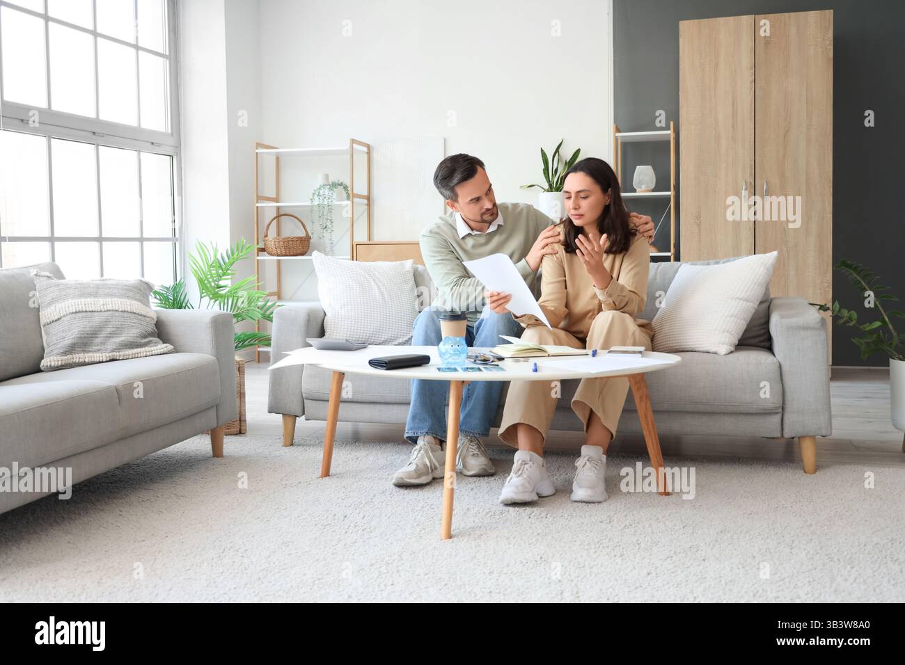 Husband calming down his upset wife at home. Bankruptcy concept Stock Photo