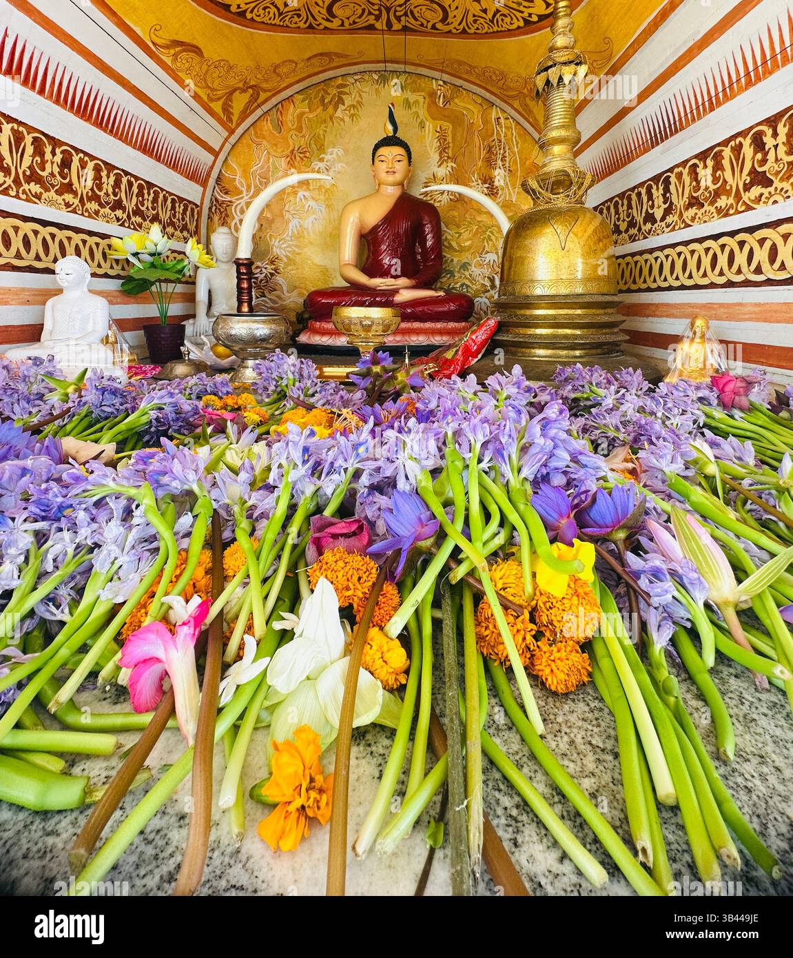 Colorful Sri Lankan flowers in focus with a serene Buddha statue blurred in the background, symbolizing peace and devotion. - Smartphone Captured Stock Image