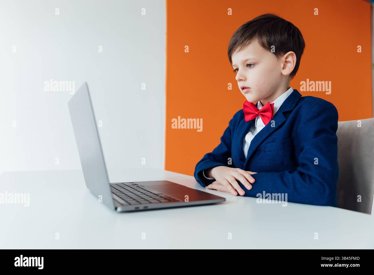 Boy in school uniform working on laptop online Stock Photo