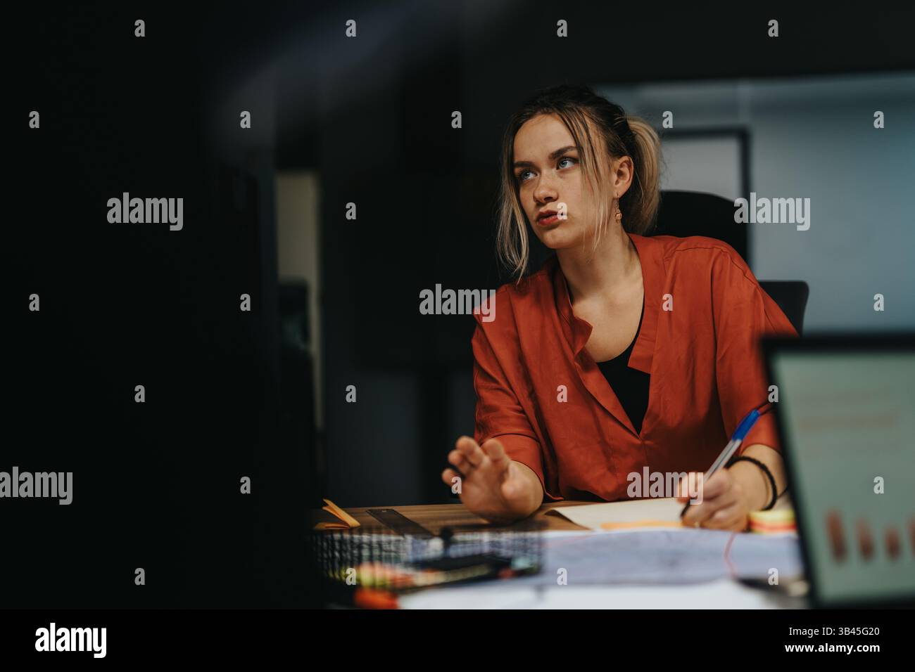 Focused woman analyzing business strategy during late evening meeting Stock Photo