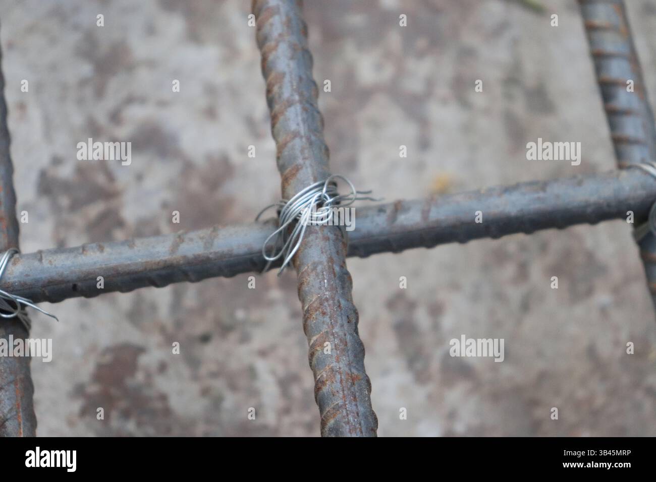 Depicts rusting rebar grid interconnected with shiny metal wire ...