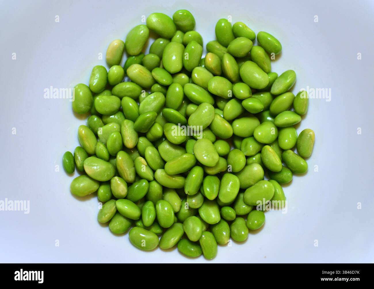 Green beans on white background top view plain. Fresh shiny edamame beans close up on a white background. Stock Photo