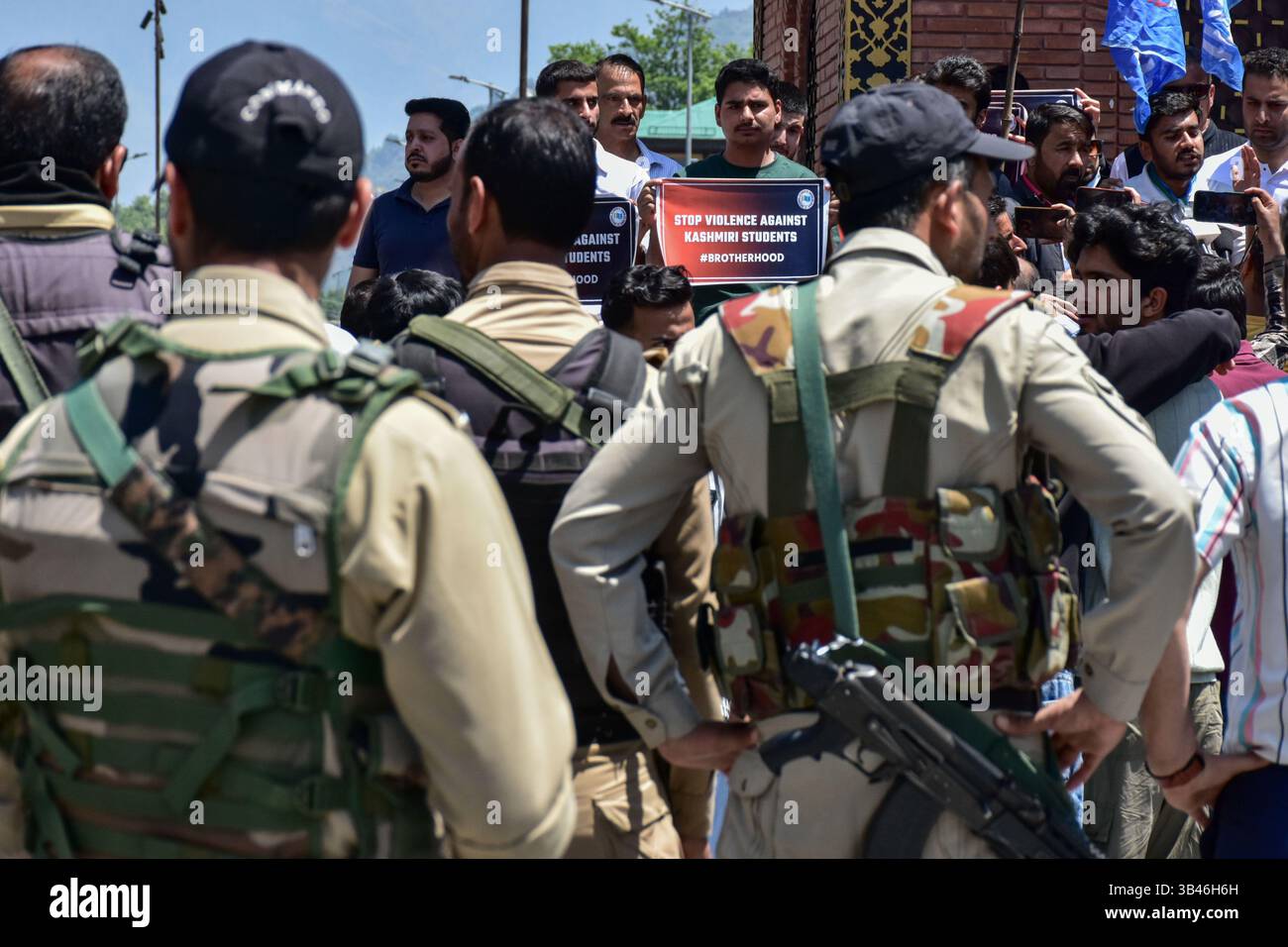 A Kashmiri student holds a placard as government forces stand guard ...