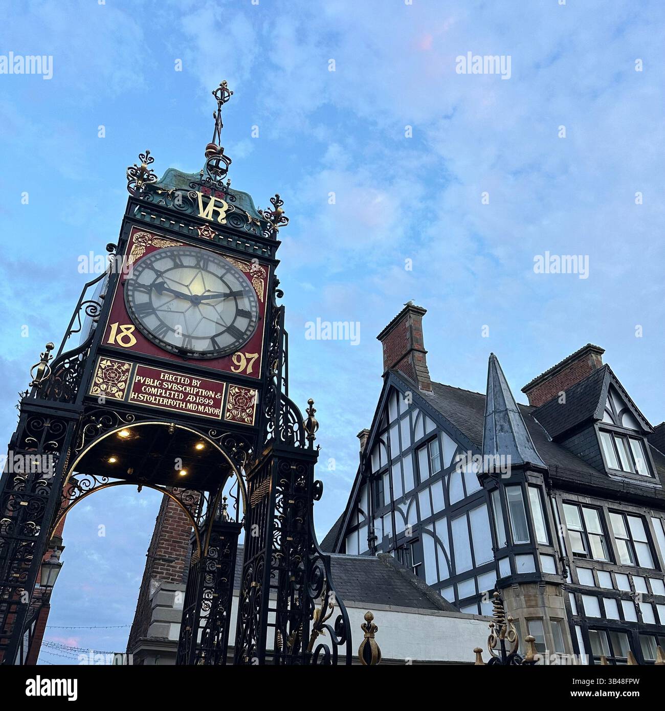 Eastgate Clock in Chester framed by blue sky and black and white timbered building on Eastgate Street. No people, taken July 2024. - Smartphone Captured Stock Image