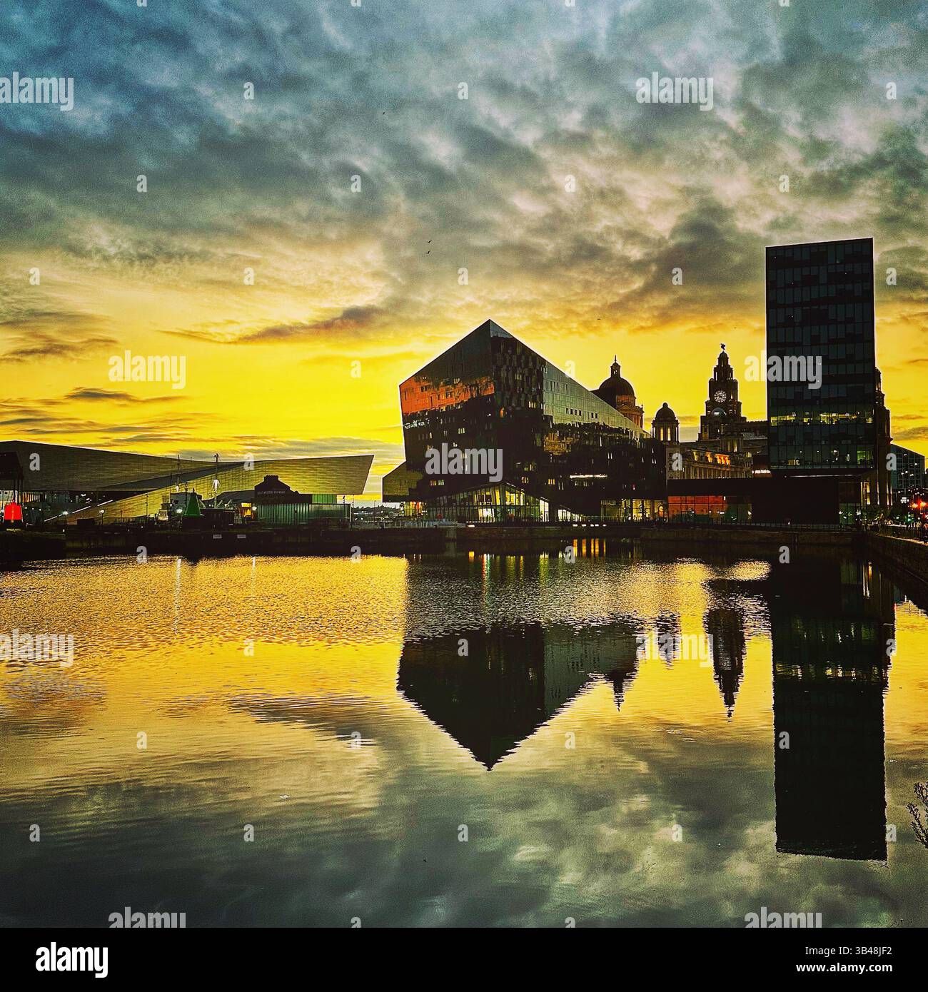 Liverpool waterfront skyline at golden hour with dramatic reflections and vibrant colours, featuring the Museum of Liverpool and the Liver Building. - Smartphone Captured Stock Image