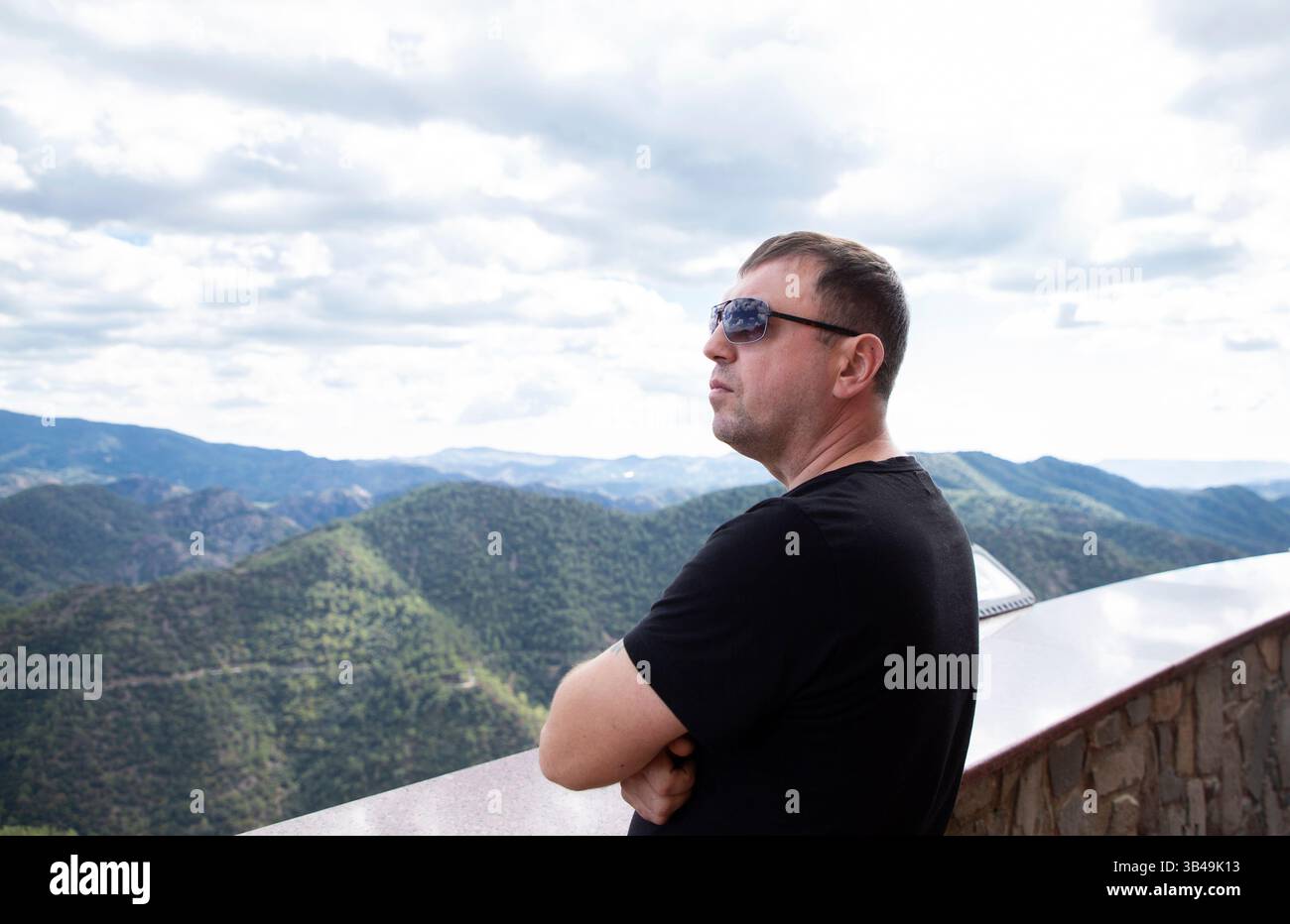 man in profile, 35-40 years old, stands on a viewing platform and admires the surrounding landscape Stock Photo