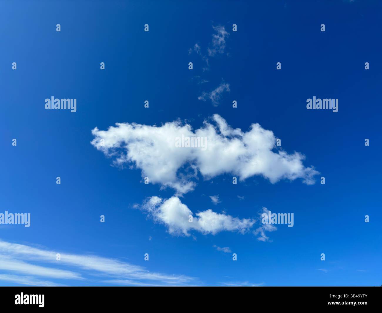 Fluffy white clouds drift against a bright blue sky on a beautiful, sunny day. - Smartphone Captured Stock Image