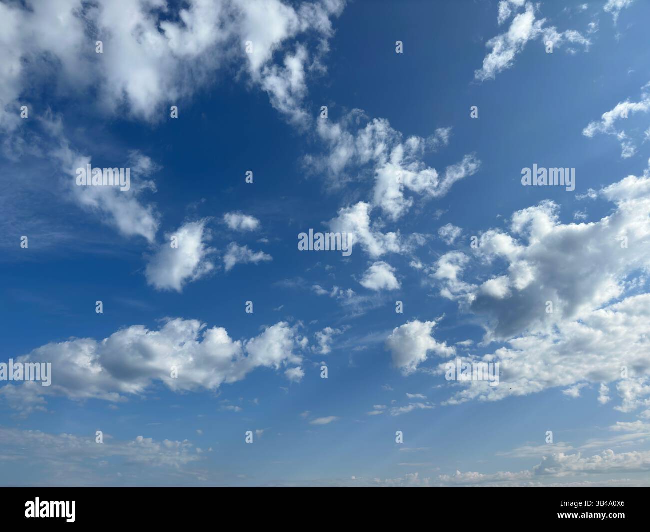 Stunning blue sky filled with white fluffy clouds on a bright, sunny day. - Smartphone Captured Stock Image