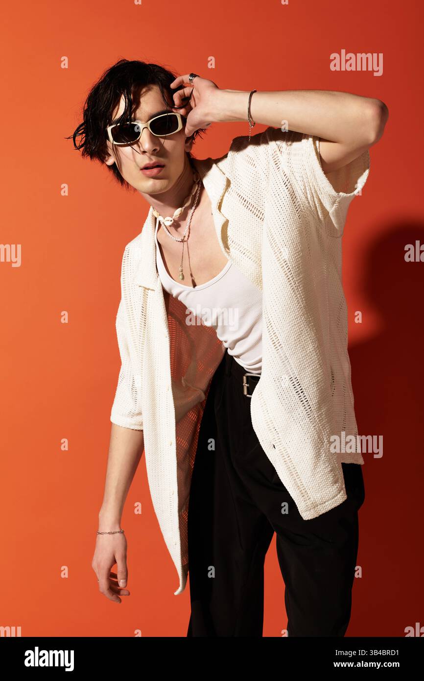 Stylish young man poses confidently in a summer outfit against a bold ...