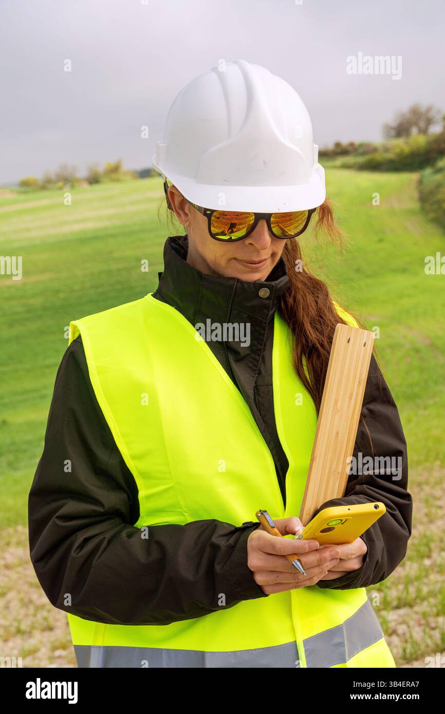 Female engineer using smartphone on construction site for renewable energy project Stock Photo