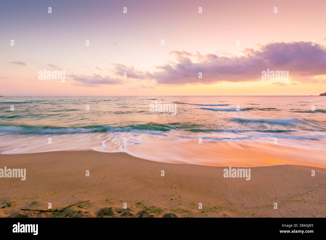 summer vacation at the sea. holiday season. beautiful purple pink seascape at sunrise. calm waves wash the golden sandy beach. fluffy clouds on the sk Stock Photo