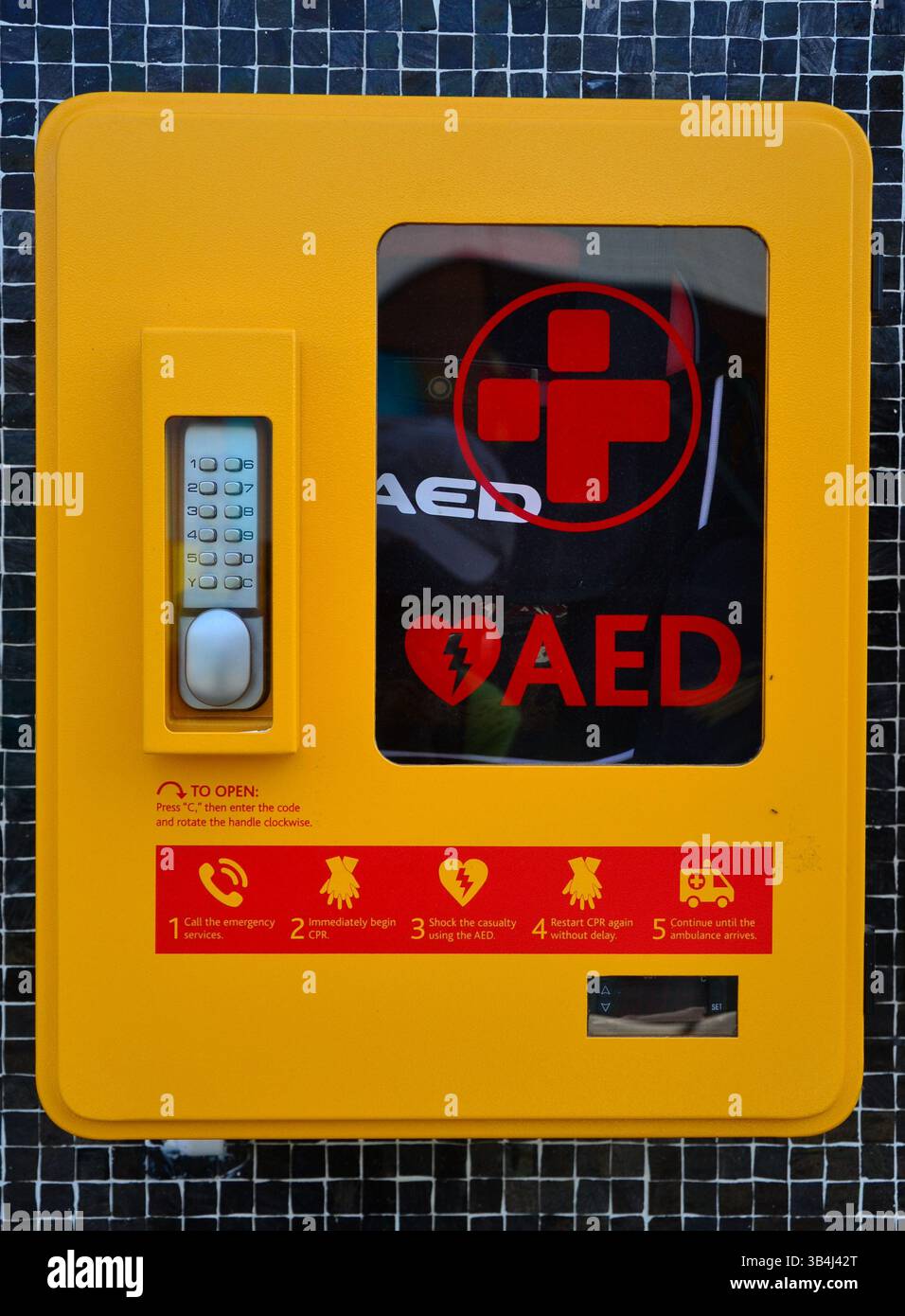 Automated External Defibrillator box mounted on a wall, a device to apply an electric charge or current to the heart to restore a normal heartbeat Stock Photo