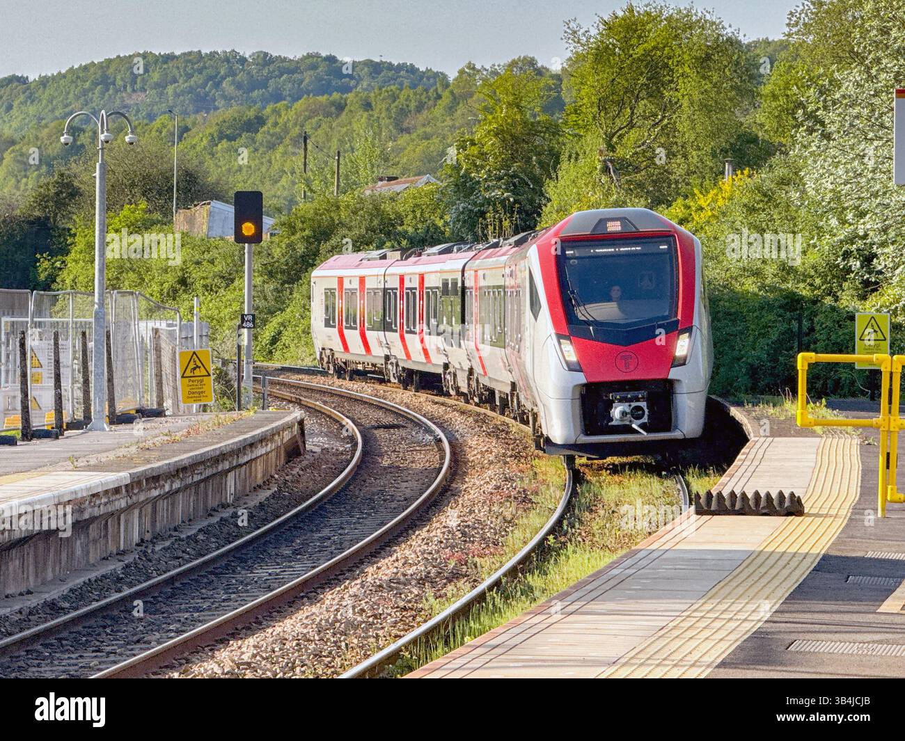 Treforest, Pontypridd, Wales, UK - 29 April 2025: Class 756 tri-mode commuter train arriving at Treforest Railway station in evening sunlight. - Smartphone Captured Stock Image