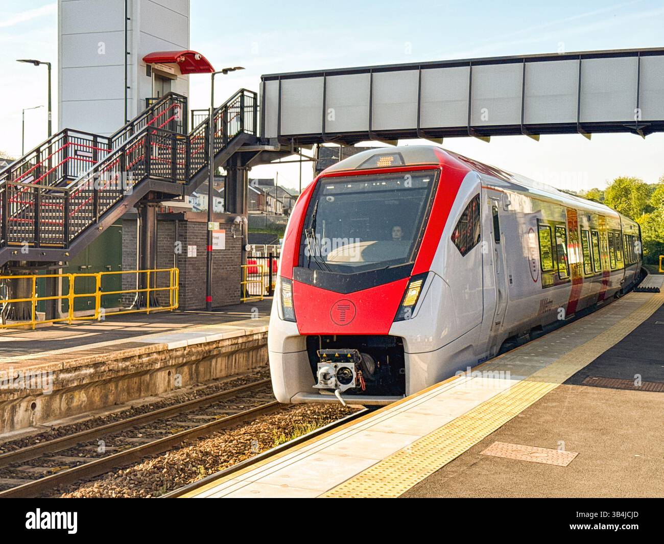 Treforest, Pontypridd, Wales, UK - 29 April 2025: Class 756 tri-mode commuter train arriving at Treforest Railway station in evening sunlight. - Smartphone Captured Stock Image