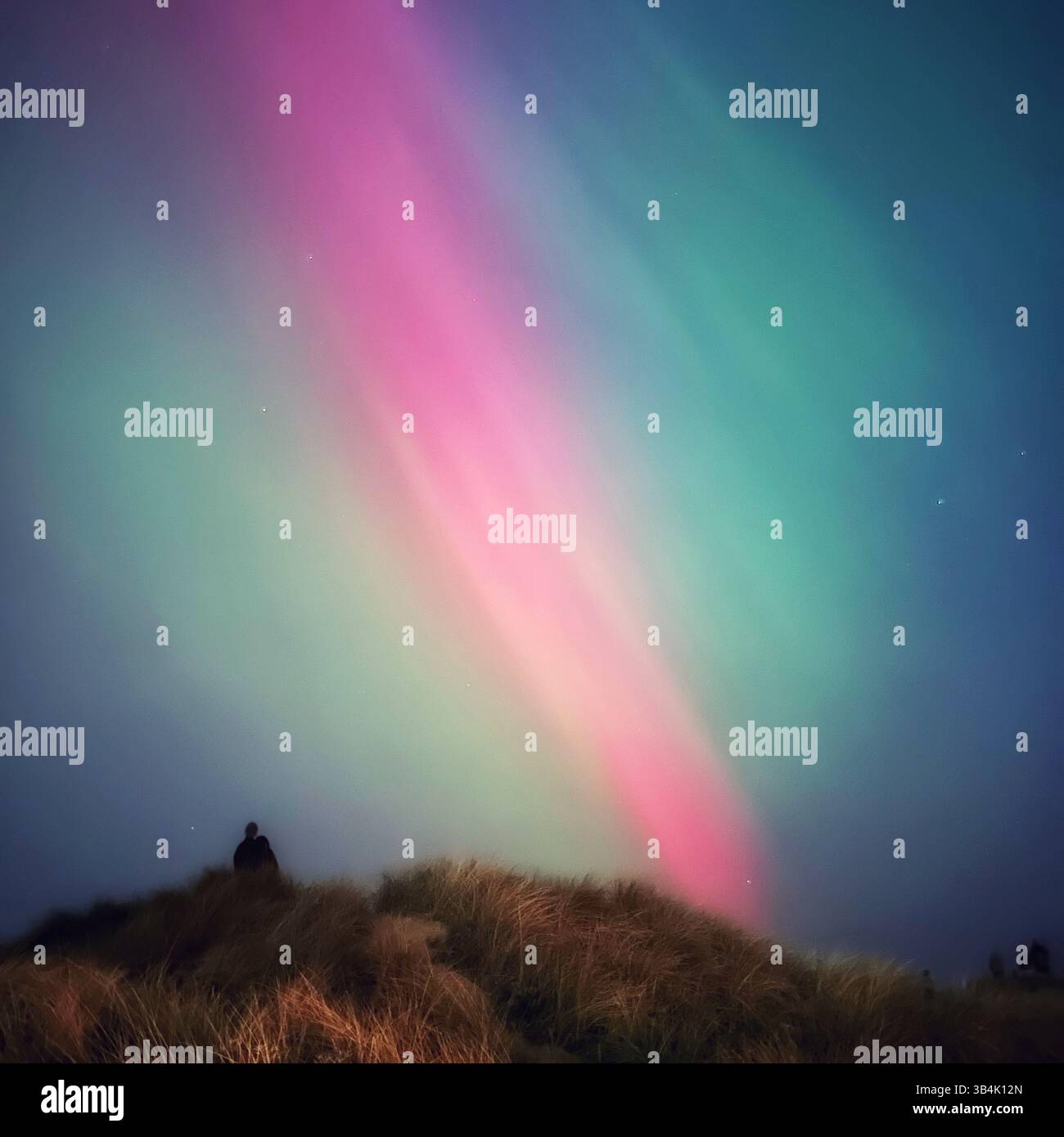Vibrant green and pink aurora borealis (northern lights) in the night sky, over Crosby beach, England, during the rare geomagnetic storm 10 May 2024. - Smartphone Captured Stock Image