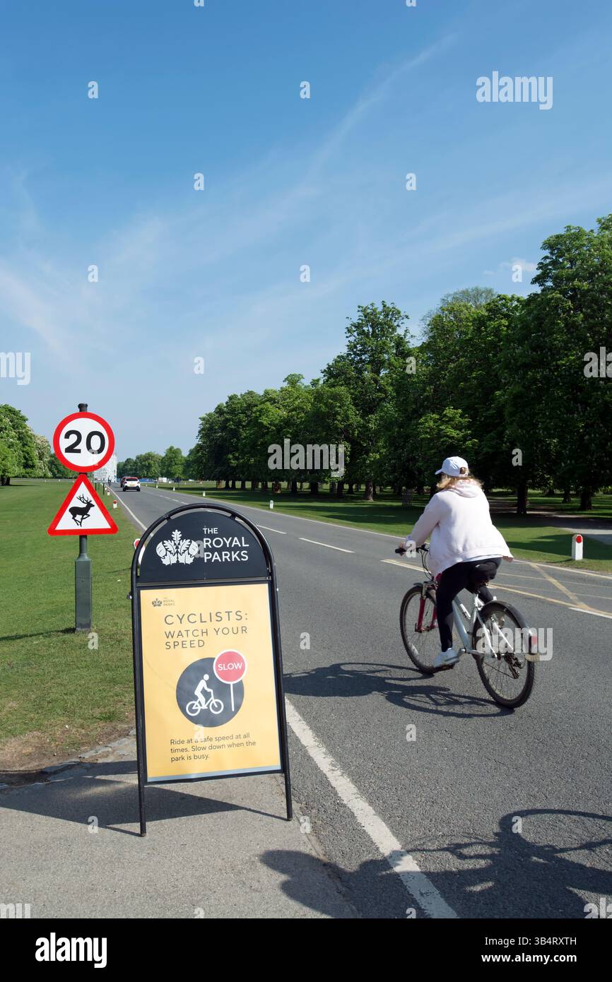 a cyclist in bushy park, southwest london, pass a sign requesting cyclists cycle at a safe speed Stock Photo