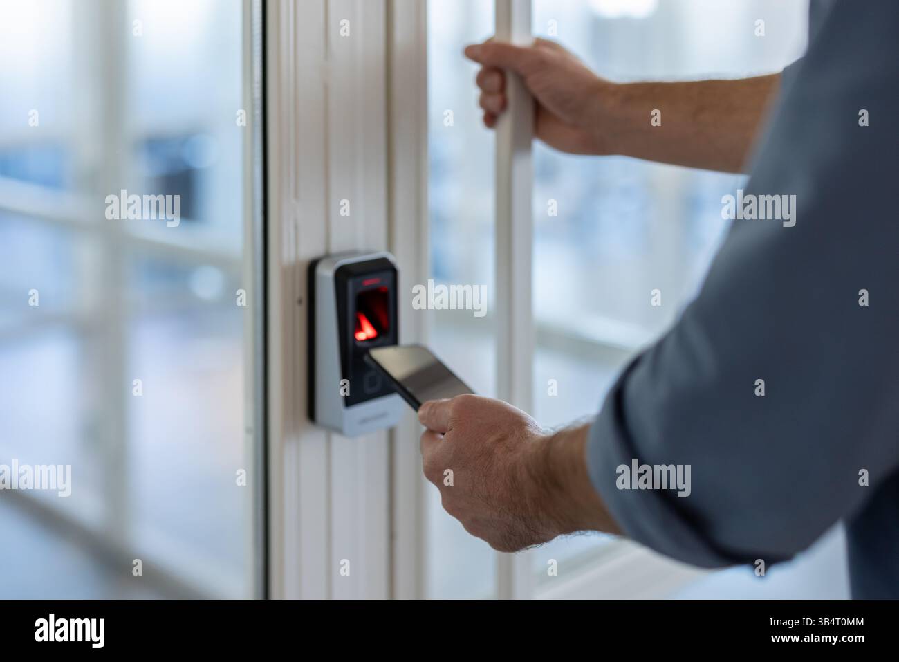 A person is using their smartphone to access an office door using a security system. Stock Photo