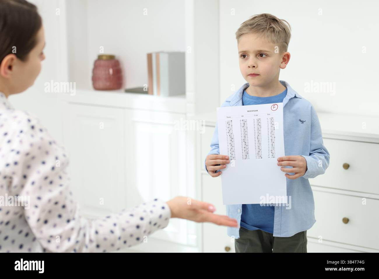 School grade. Sad boy showing answer sheet with bad mark to his mother ...