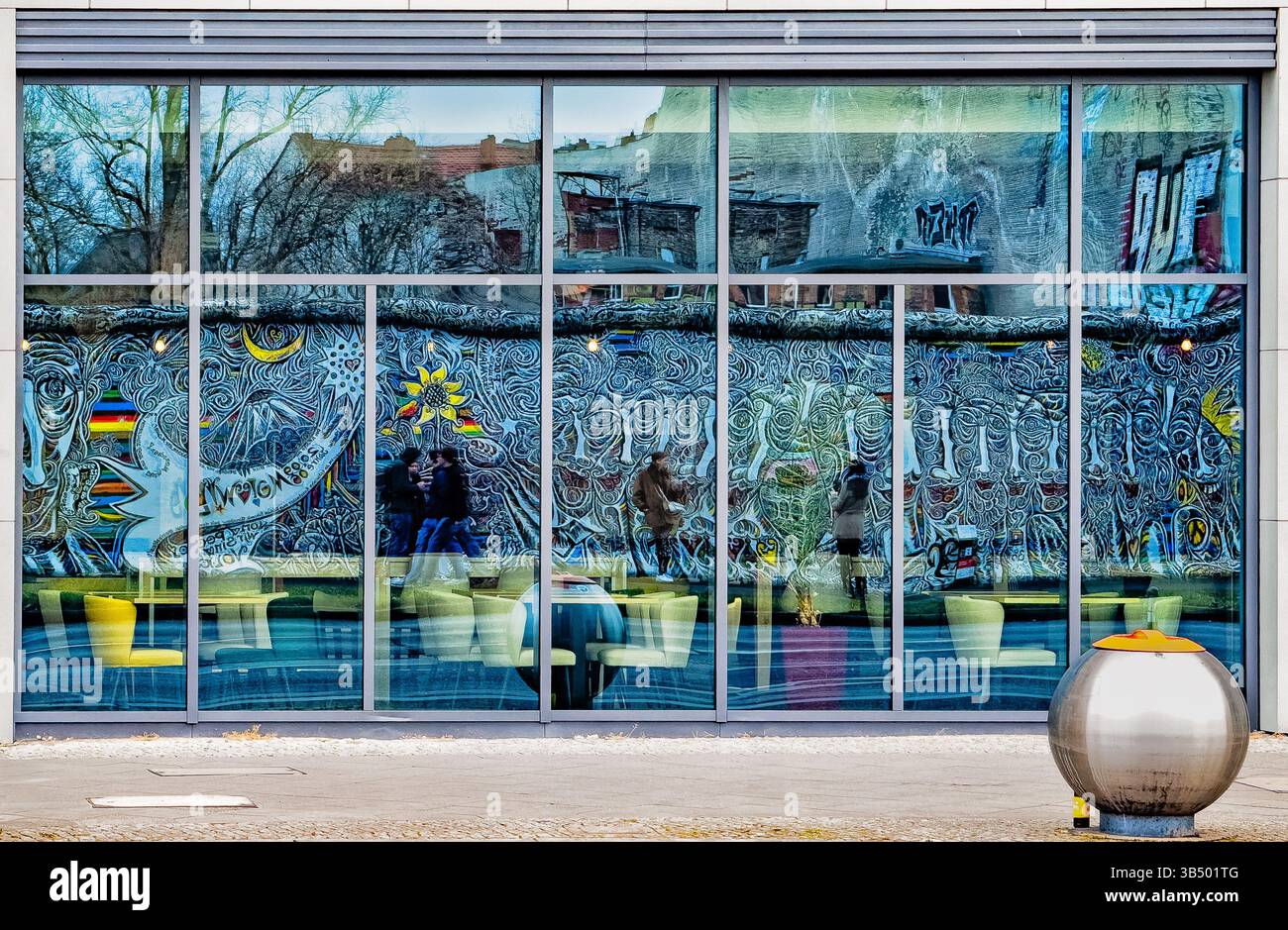 The Berlin Wall (East Side Gallery) reflected in the glass windows of a building on the opposite side of the street - Smartphone Captured Stock Image