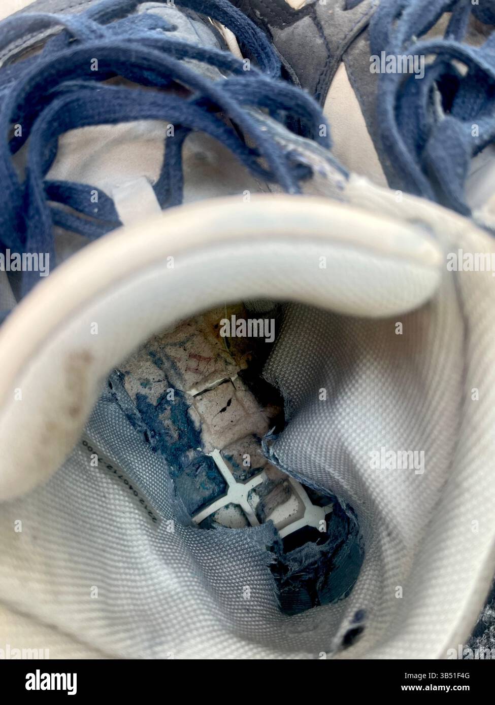 Close-up of old worn-out trainers with heavily damaged insole, showing visible wear from long-term use and poor interior condition - Smartphone Captured Stock Image