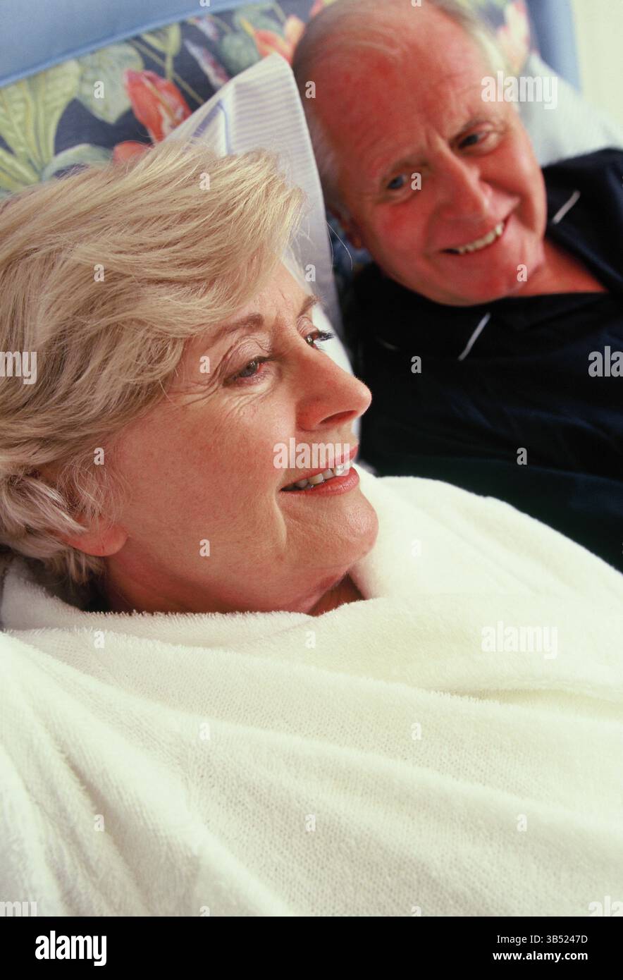 Senior man & woman lying in bed. Stock Photo