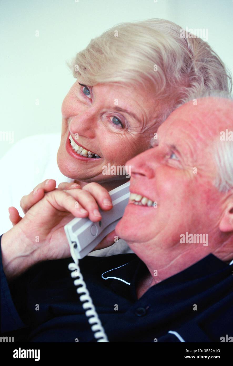 Close up of senior man & woman in pyjamas talking on the telephone. Stock Photo