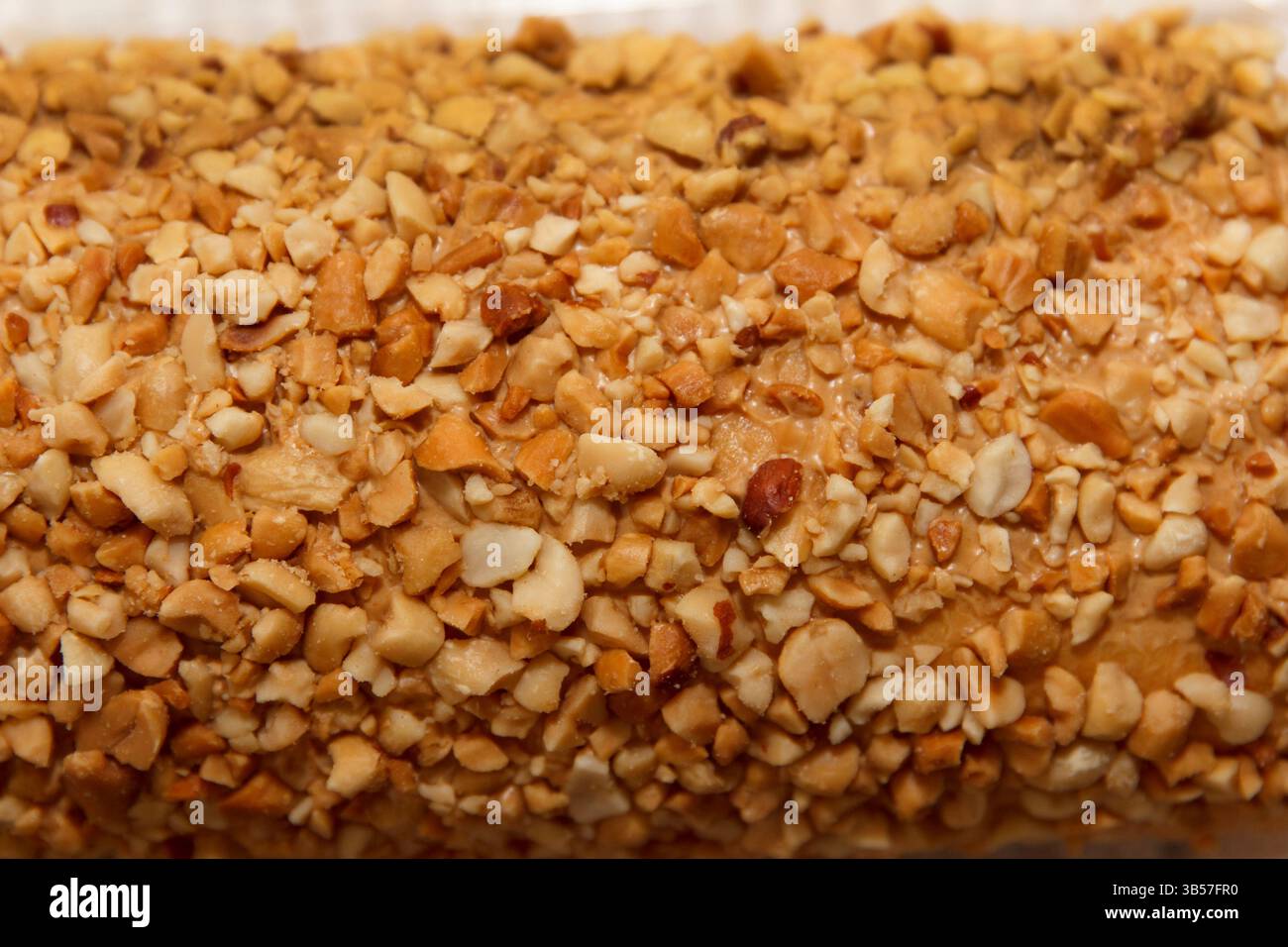 Crunchy crushed peanut texture covering a dessert surface, captured in close-up on a soft neutral background for culinary concept Stock Photo