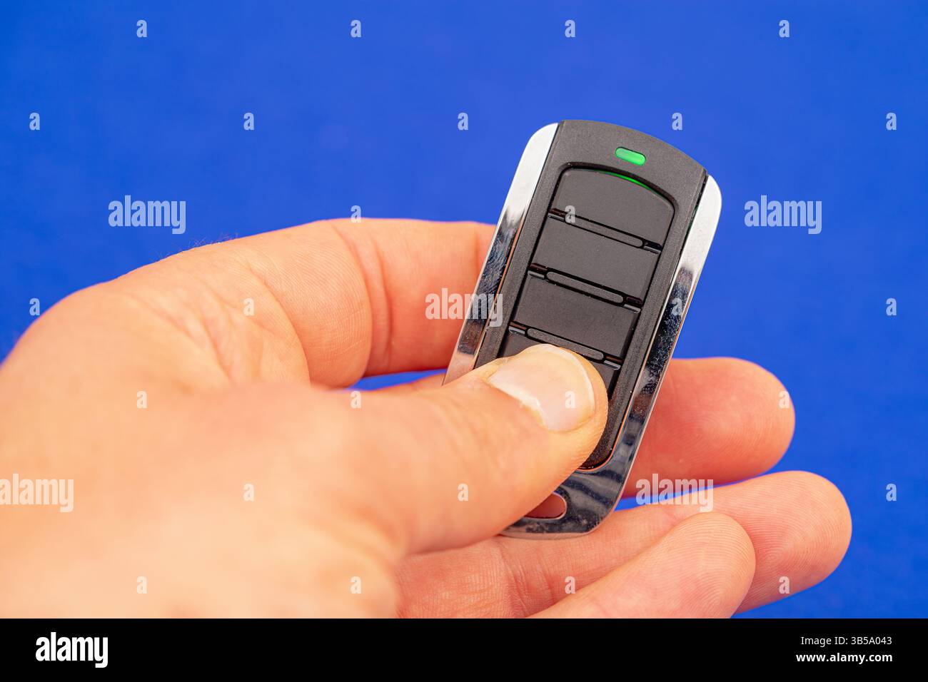 four-button remote control for opening garage doors held in hand on blue background Stock Photo