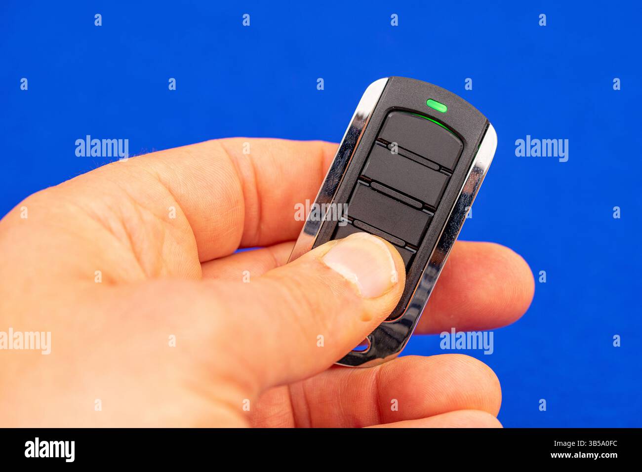 four-button remote control for opening garage doors held in hand on blue background Stock Photo
