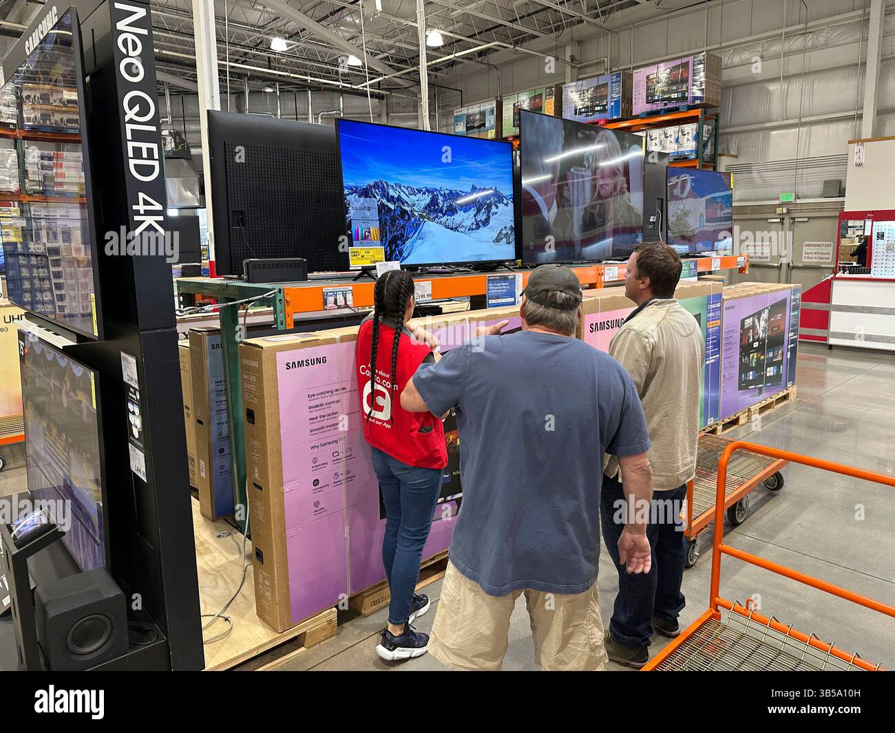 Shoppers consider a large-screen television with the help of a sales ...